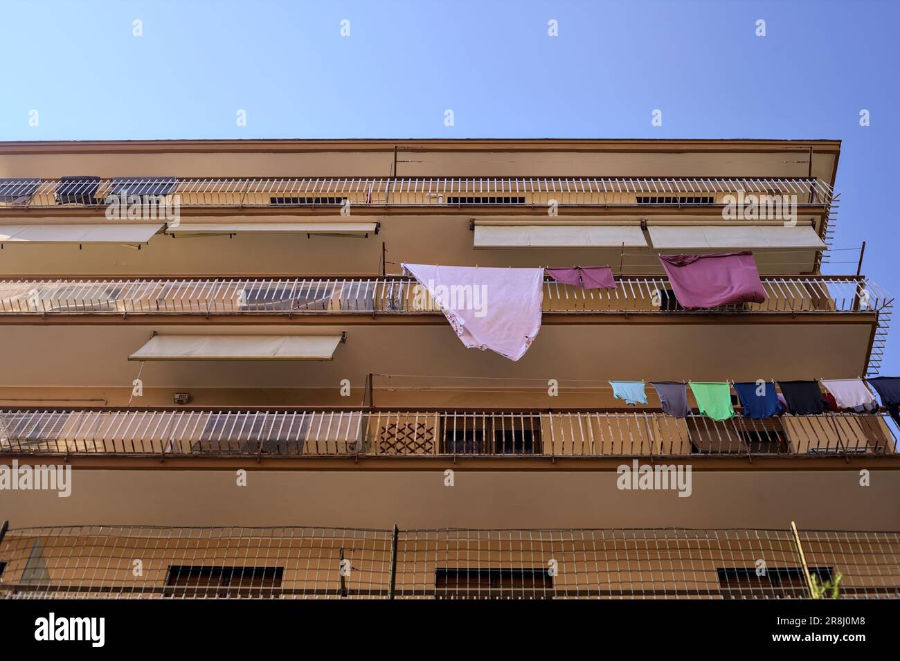 Balconi di un condominio con abiti appesi in una giornata di sole visto dal basso Foto Stock