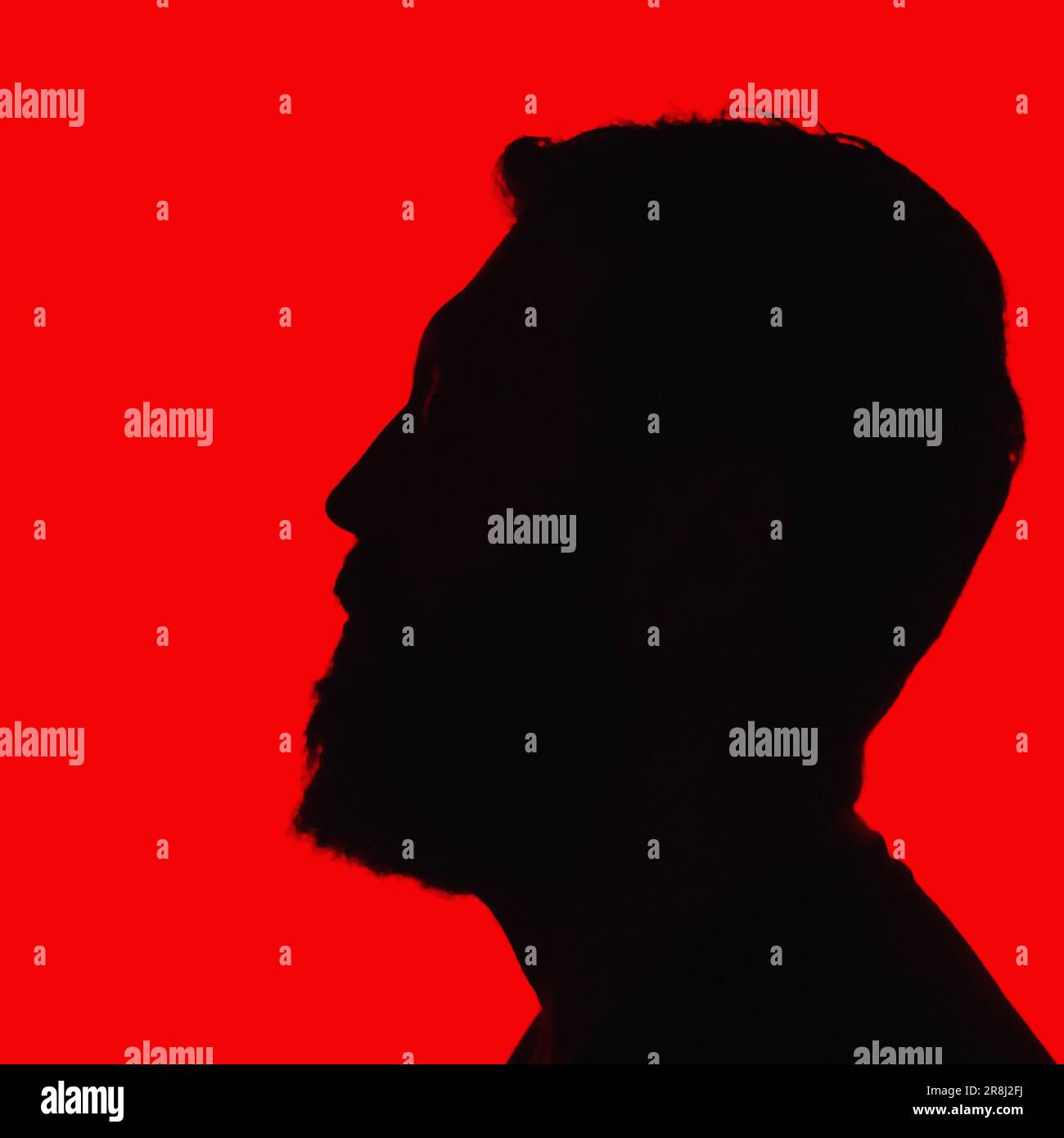 Una persona anonima in una silhouette rossa si alza a guardare con un'espressione di contemplazione Foto Stock