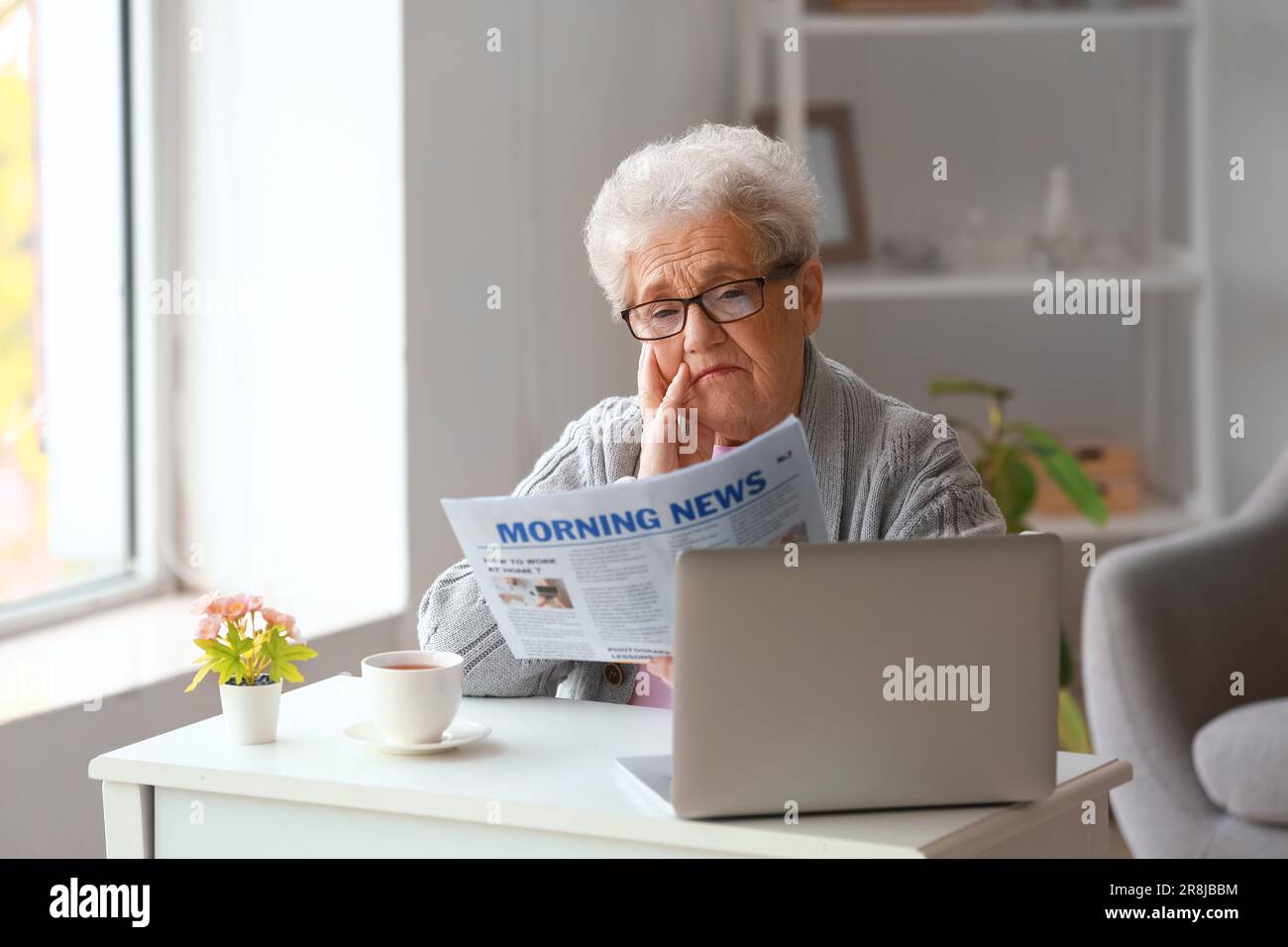 Donna anziana che legge giornale a casa Foto Stock