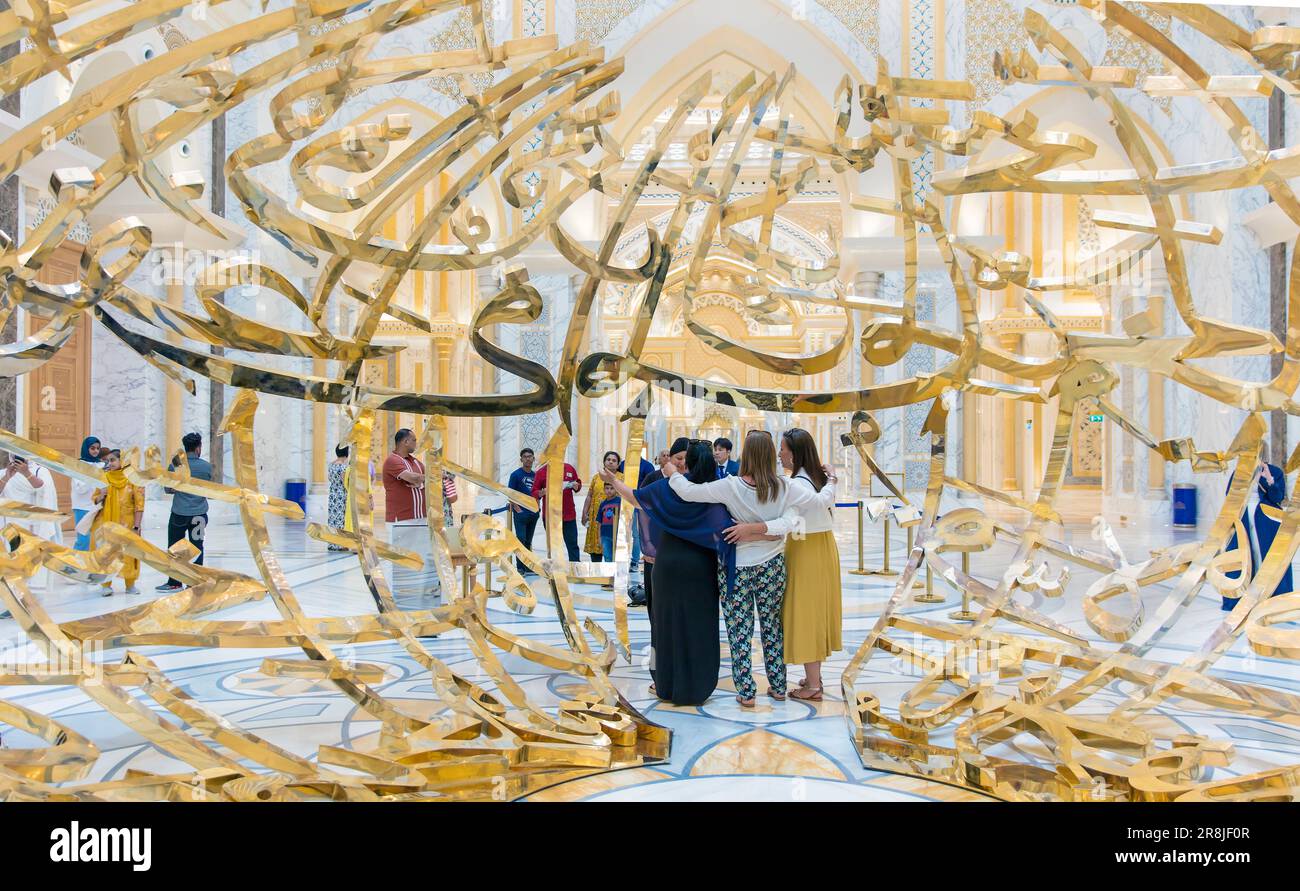 La gente posa per le fotografie all'interno del globo di Calligraphy dorato all'interno del palazzo presidenziale di Qasr al Watan, Abu Dhabi, Emirati Arabi Uniti Foto Stock