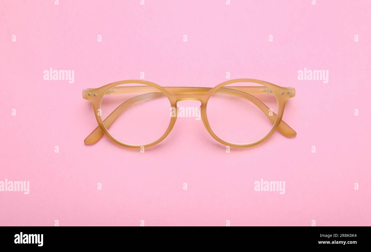 Occhiali con lenti correttive su sfondo rosa, vista dall'alto Foto Stock