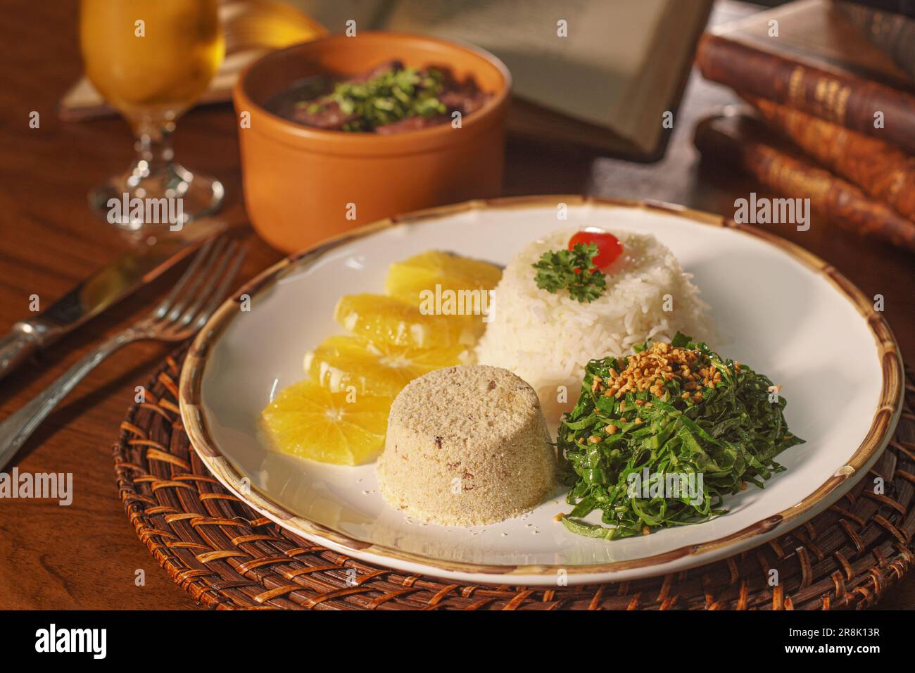 Bellissimo piatto di feijoada con birra. Sullo sfondo vecchi libri Foto Stock
