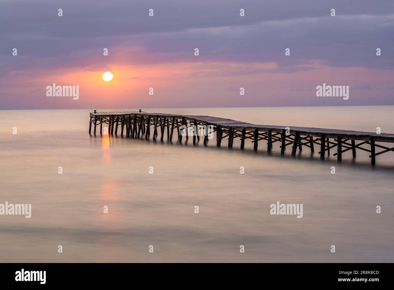 Alba estiva su un molo di legno su una spiaggia di Platja de muro (Maiorca, Isole Baleari, Spagna). Esempio: Amanecer veraniego en un muelle de madera en muro Foto Stock