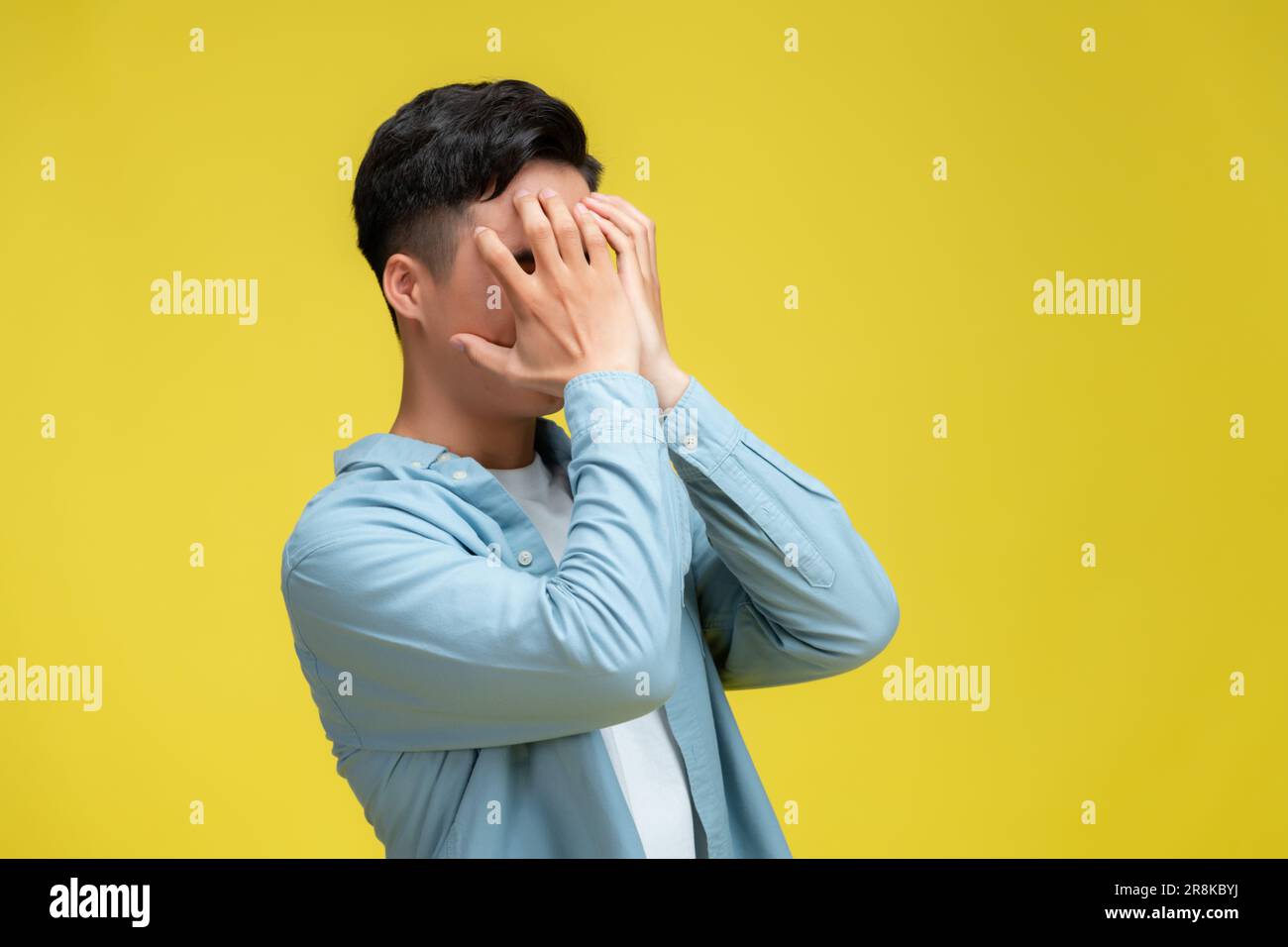Immagine stock di uomo d'affari che copre gli occhi con le mani, su sfondo giallo Foto Stock