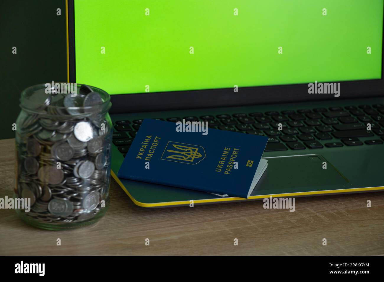 computer portatile con schermo verde, un centesimo in banca e un passaporto Foto Stock