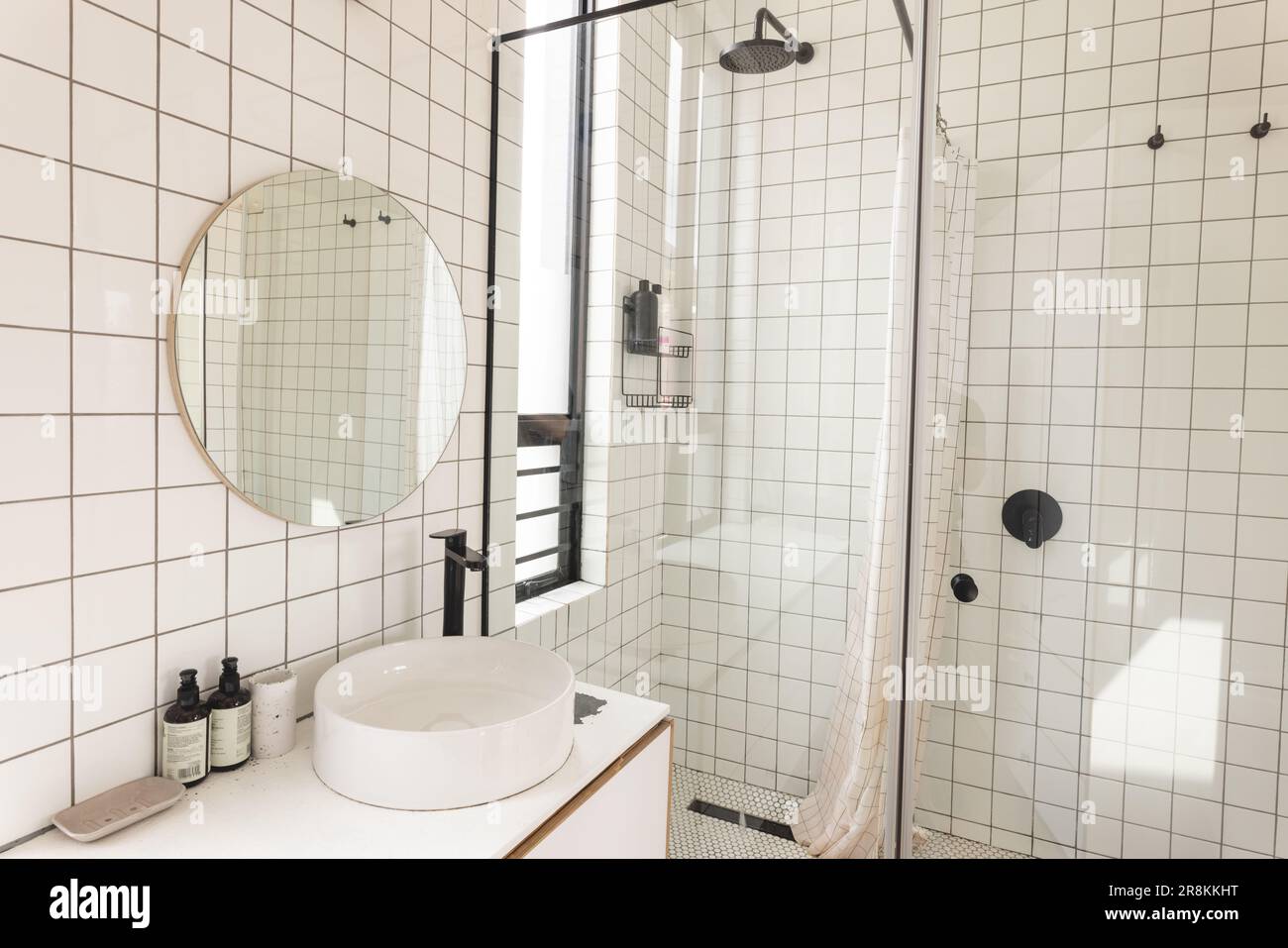 Vista degli interni luminosi e moderni del bagno con piastrelle bianche e cabina doccia in vetro Foto Stock