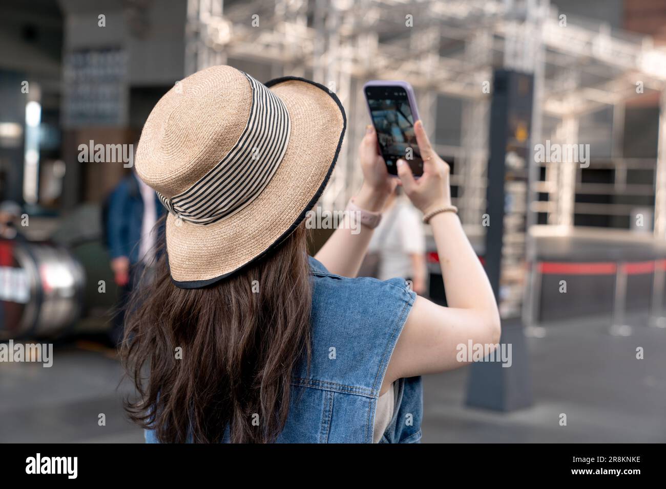 Una giovane donna in un cappello di paglia, scattando foto con il suo telefono Foto Stock