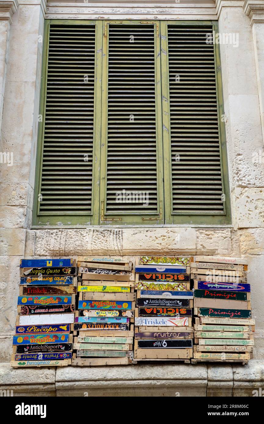 Pila di cesti di frutta in legno vuoti di fronte alla tapparella verde di legno dell'isola di ortigia in sicilia Foto Stock