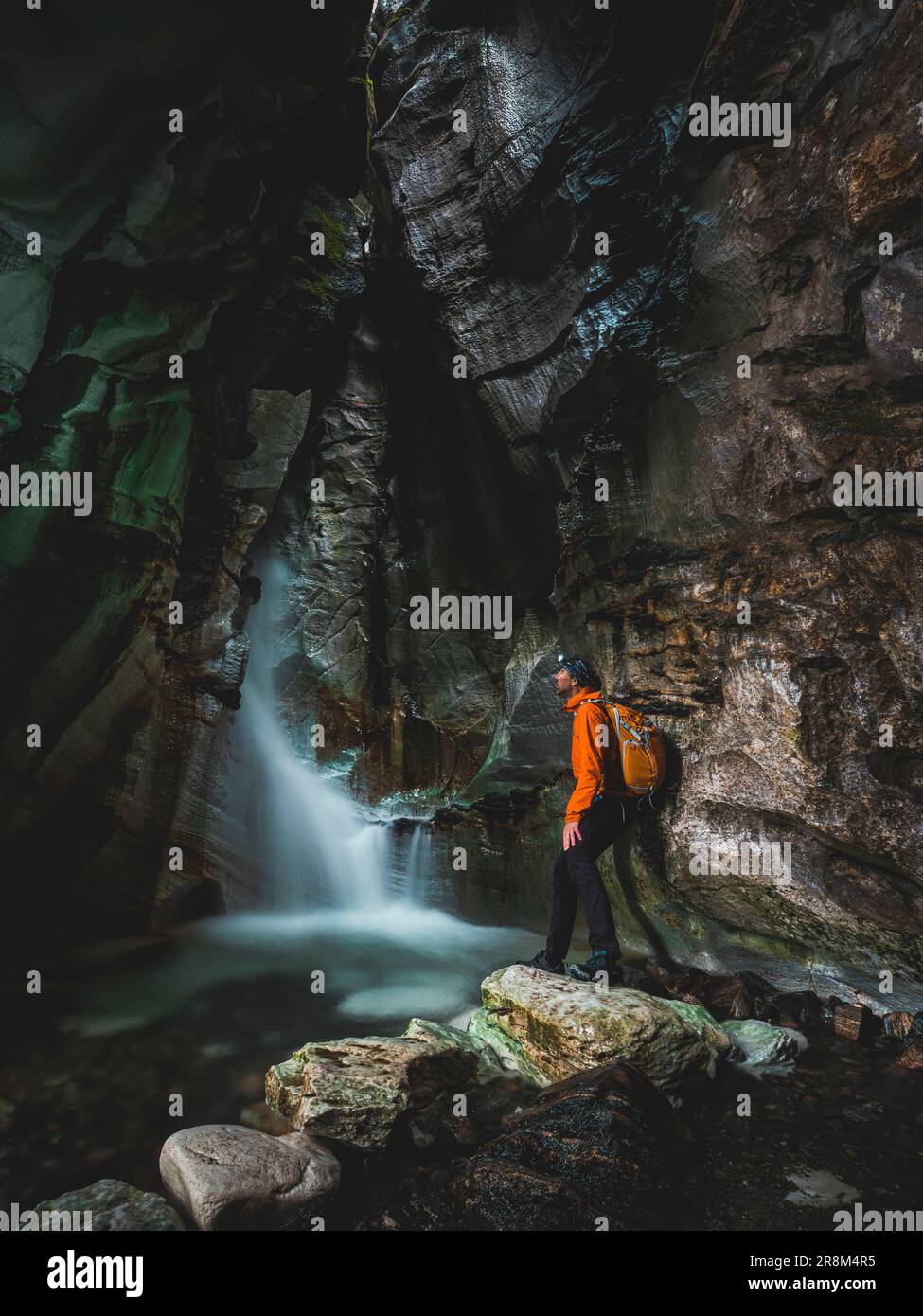 Uomo che guarda la cascata mentre esplora la grotta Foto Stock