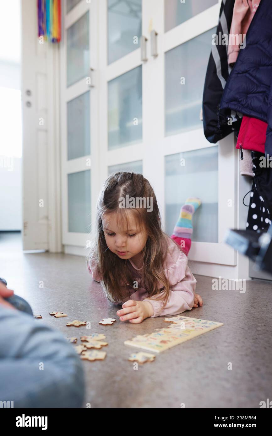 Ragazza sdraiata sul pavimento e che fa rompicapo Foto Stock