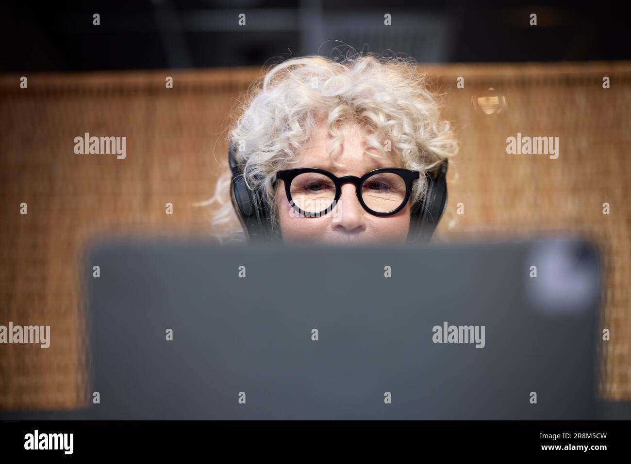 Donna anziana con cuffie che utilizza un tablet Foto Stock
