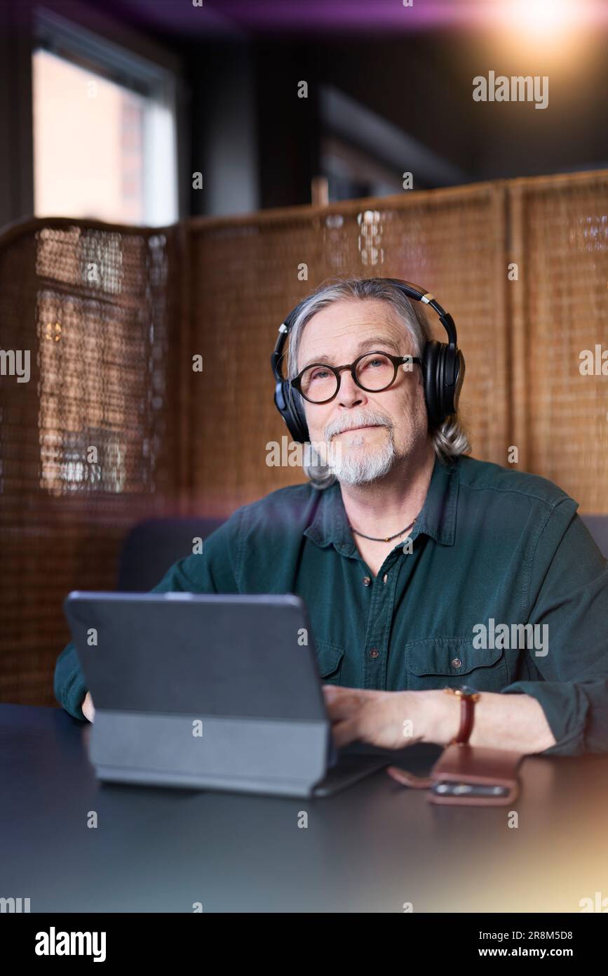 Ritratto di un uomo anziano con le cuffie utilizzando un tablet Foto Stock