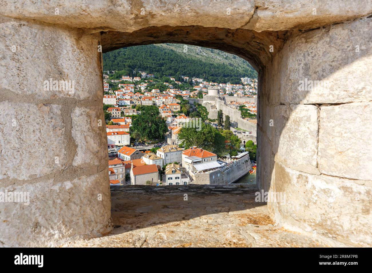 Vista della città vecchia di Dubrovnik attraverso un'apertura nella parete della fortezza in viaggio in Croazia Foto Stock