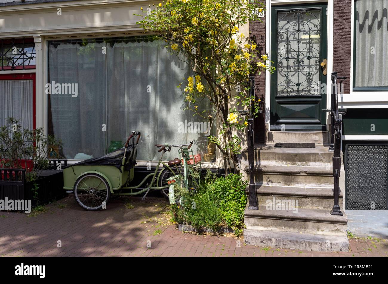 Una bicicletta verde in una strada ad Amsterdam, Paesi Bassi. Foto Stock