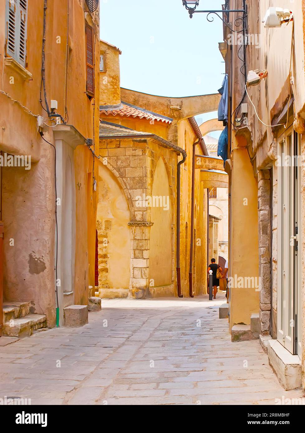 La stretta strada di Ville Haute (città alta) con vista sulle mura della chiesa di Sainte-Marie-majeure con contrafforti volanti, Bonifacio, Corsica, Fran Foto Stock