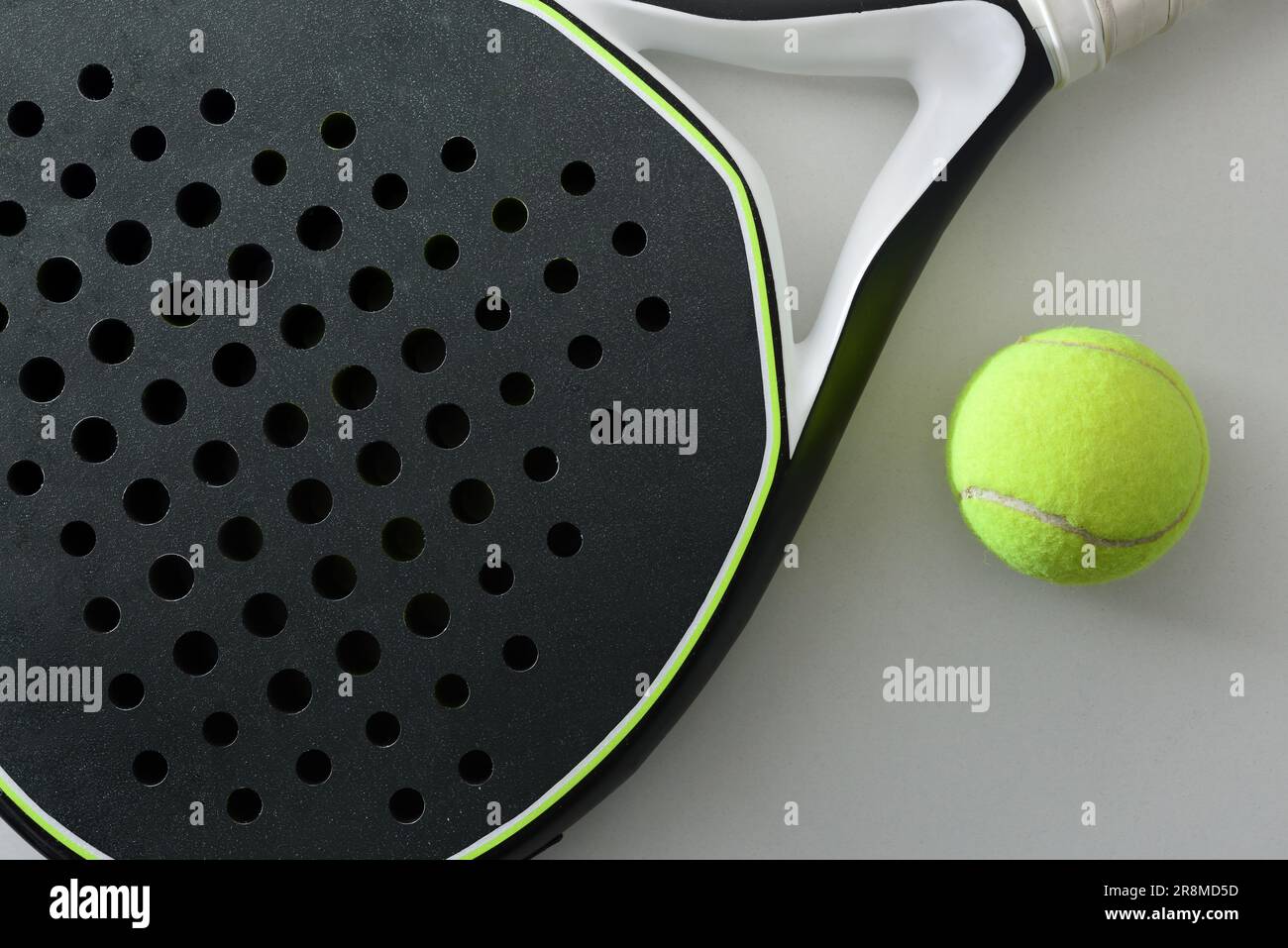 Dettaglio di racchetta da paddle tennis bianca e nera e palla su un tavolo bianco. Vista dall'alto. Foto Stock