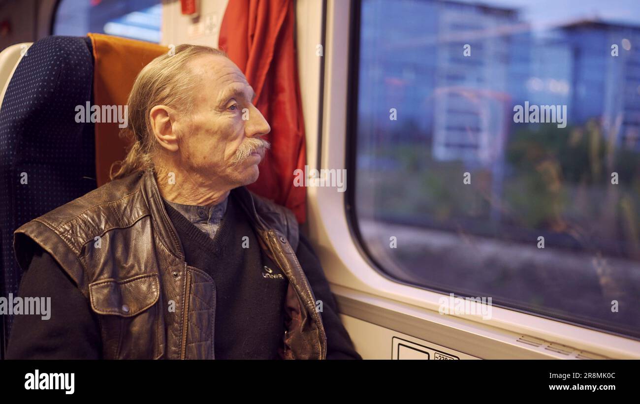 Primo piano di anziani con gli occhiali viaggia in un treno e guarda fuori dalla finestra Foto Stock