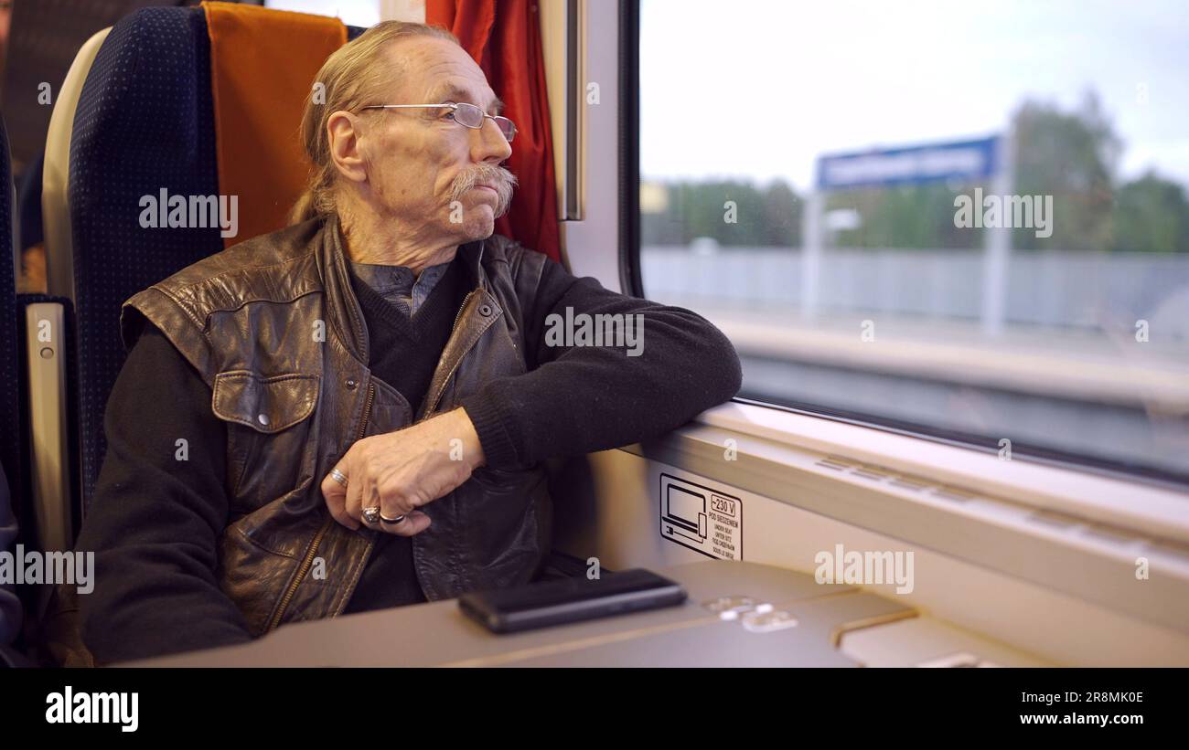 Primo piano di anziani con gli occhiali viaggia in un treno e guarda fuori dalla finestra Foto Stock