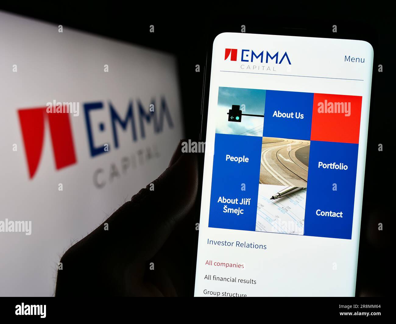 Persona che possiede il cellulare con il sito web della società di investimento ceca EMMA Capital sullo schermo davanti al logo. Concentrarsi sul centro del display del telefono. Foto Stock