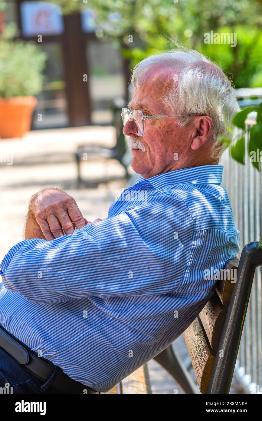 Vecchio uomo in pensione con capelli grigi seduto su panca del giardino nel centro della città - Tours, Indre-et-Loire (37), Francia. Foto Stock