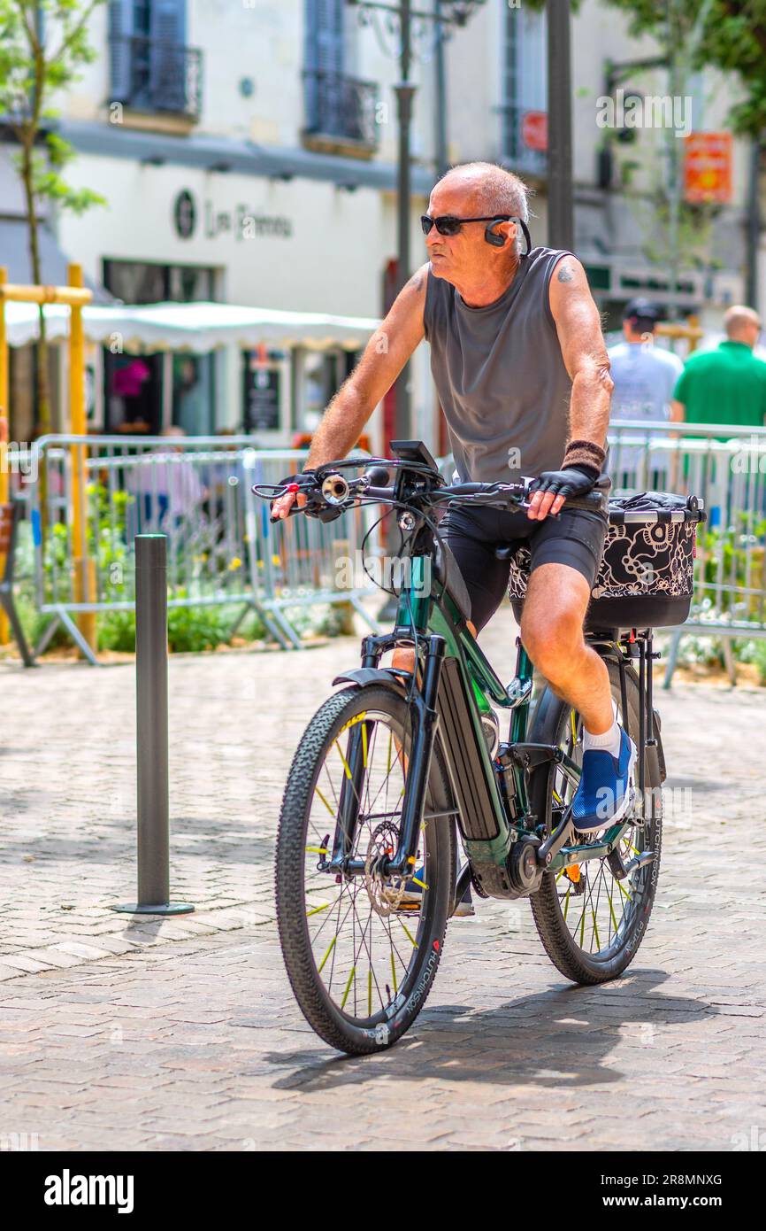 Uomo in T-shirt e pantaloncini in bici elettrica attraverso il centro della città - Tours, Indre-et-Loire (37), Francia. Foto Stock