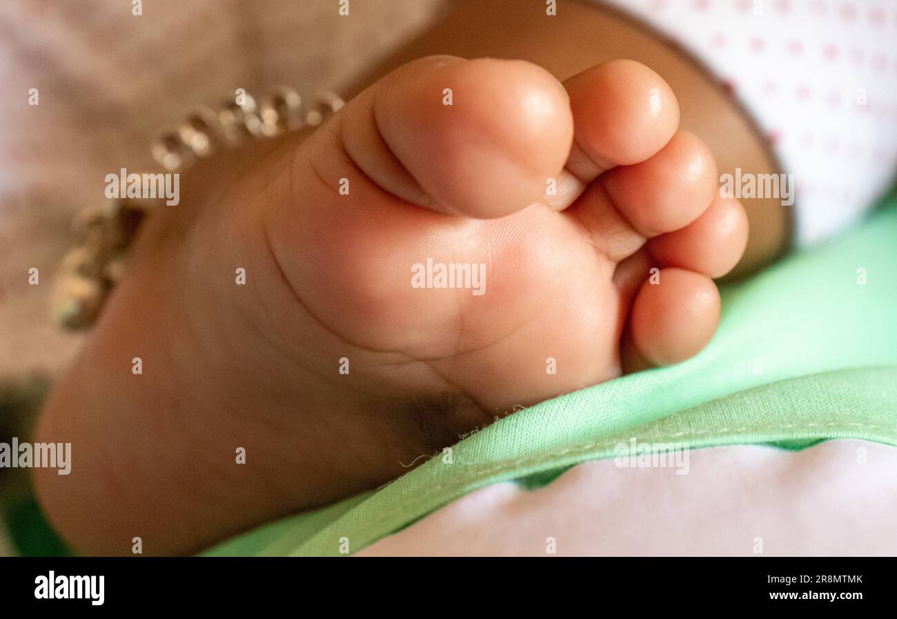 Un primo piano del piede di un neonato con una caviglia appoggiata su una confortevole coperta. Foto Stock
