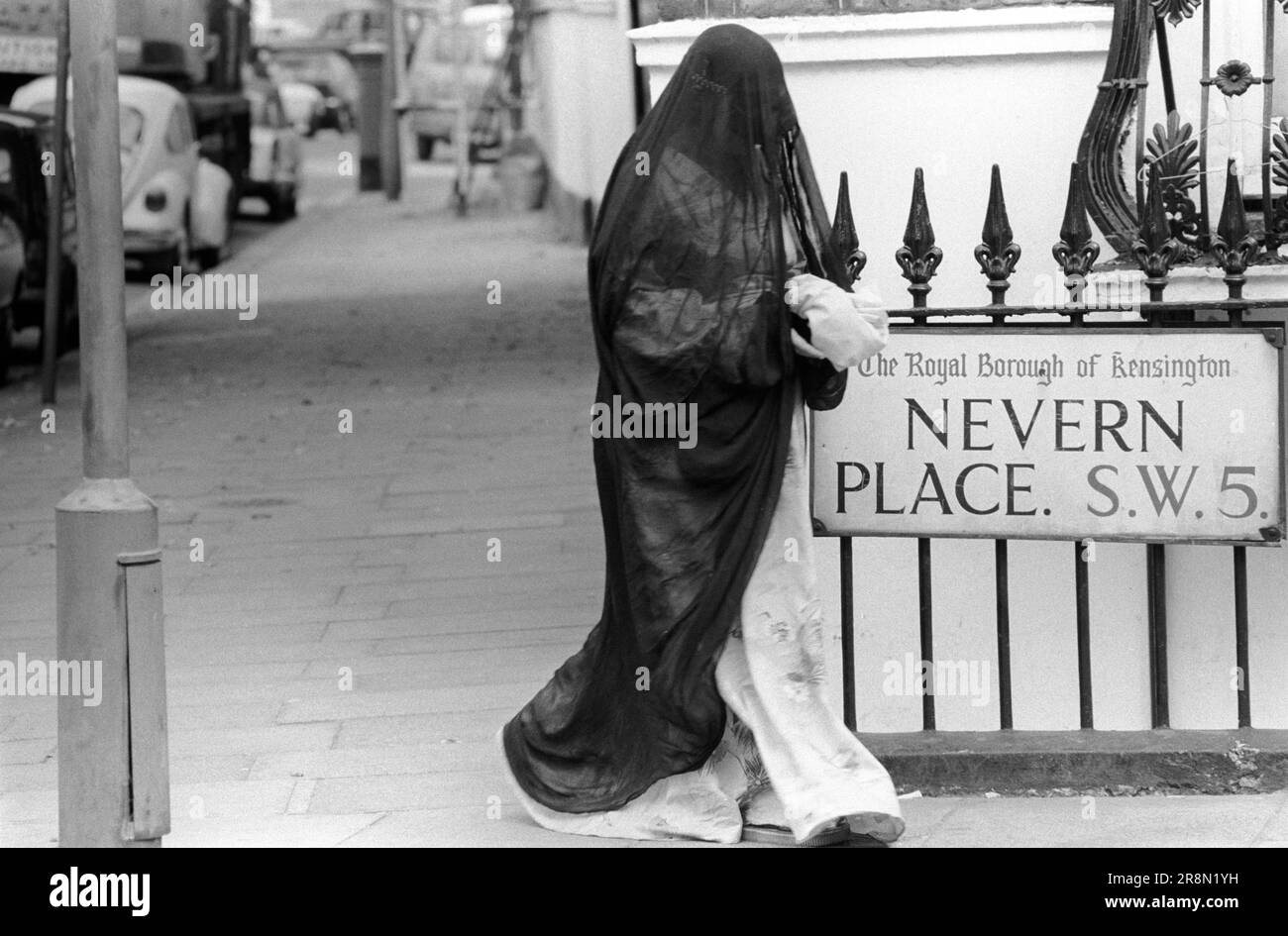 Poveri arabi a Londra negli anni '1970 Le persone del Medio Oriente sono venute in Gran Bretagna per ricevere assistenza sanitaria sovvenzionata nelle cliniche di Harley Street. Sono stati principalmente in alberghi economici a Earls Court. Una donna che indossa una copertura integrale in burqa copre tutto il corpo dalla cima della testa al suolo. Earls Court, Londra, Inghilterra intorno agli anni '1977 1970 UK HOMER SYKES Foto Stock