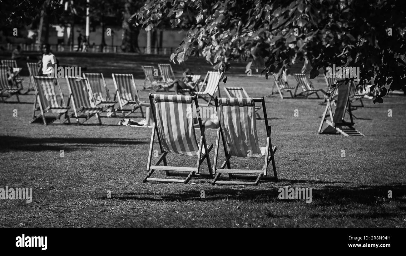 Sedie a sdraio e bagni di sole a St. James's Park durante l'ondata di calore dell'estate. Foto Stock