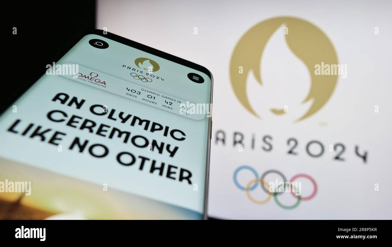 Telefono cellulare con il sito Web delle Olimpiadi estive di Parigi 2024 sullo schermo davanti al logo. Mettere a fuoco in alto a sinistra sul display del telefono. Foto Stock