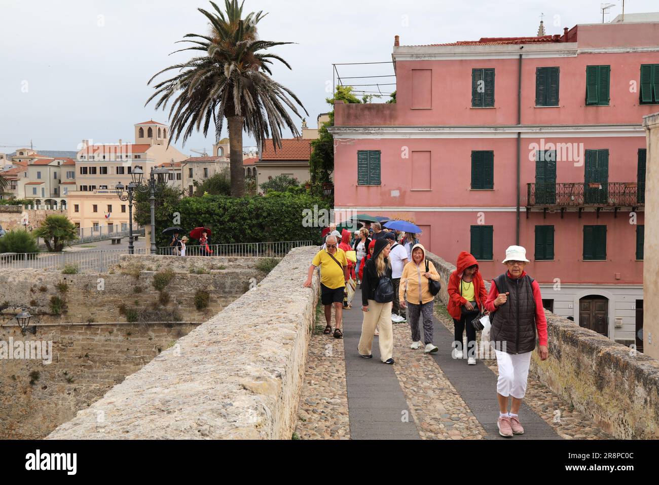 ALGHERO, ITALIA - 29 MAGGIO 2023: Le persone prendono parte a un tour della città in condizioni di pioggia Alghero città dell'isola Sardegna, Italia. Foto Stock