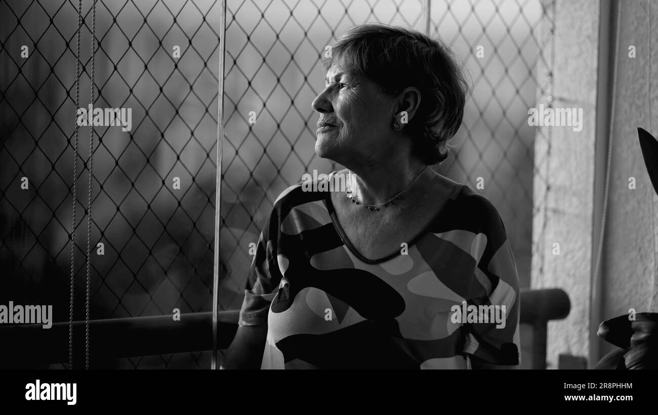 Solitudine di riflessione  donna anziana depressa a 70 anni, che ricorda i momenti della vita nella quiete monocromatica, in bianco e nero Foto Stock