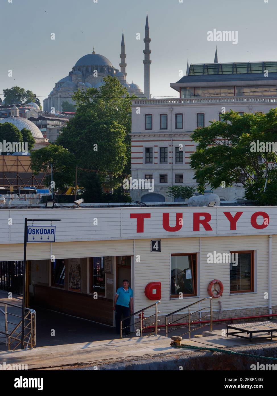 Ufficiale in piedi presso il terminal dei traghetti con la Moschea di Suleymaniye sulla collina alle spalle, Istanbul, Turchia Foto Stock