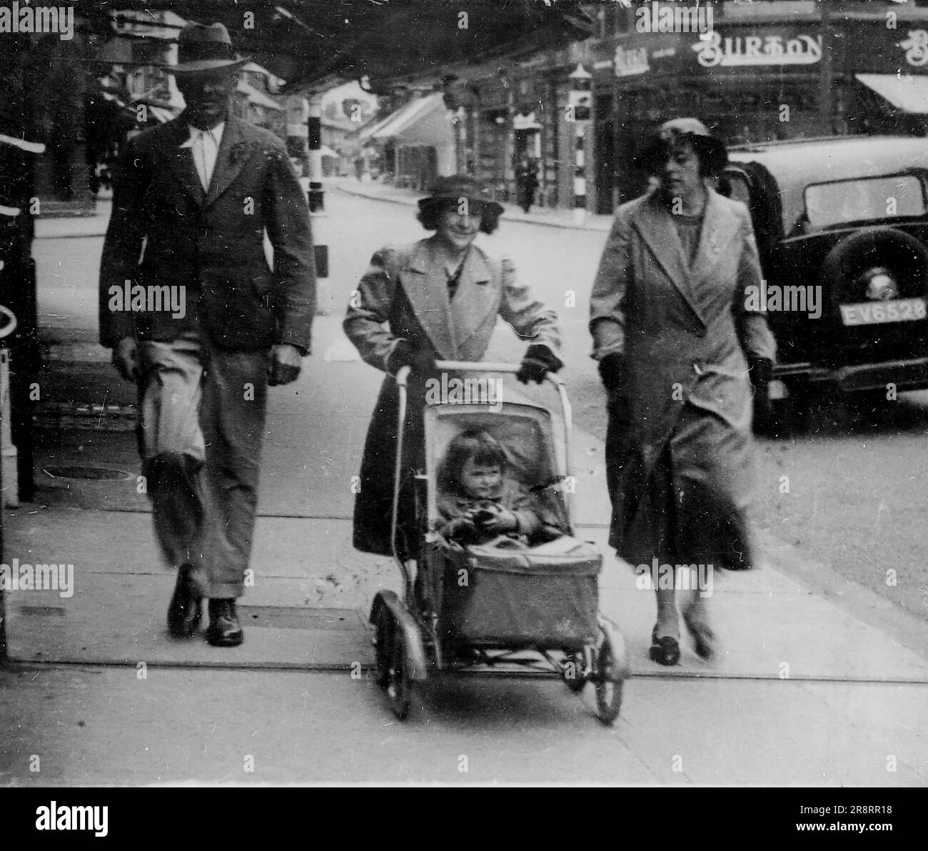 Un gruppo familiare che include un bambino in una carrozzina del periodo, con un negozio Burton sullo sfondo. Si tratta di una fotografia tratta da un album di scatti principalmente istantanee, c1929, durante l'occupazione della Palestina da parte dell'esercito britannico, con foto dalla Palestina e dal Regno Unito tra cui devil's Jump vicino a Churt nel Surrey e devil's Punch Bowl. L'addestramento sembra essere a Hursley Camp, vicino a Winchester. La Gran Bretagna amministrò la Palestina per conto della società delle Nazioni tra il 1920 e il 1948, un periodo denominato "mandato britannico”. Foto Stock