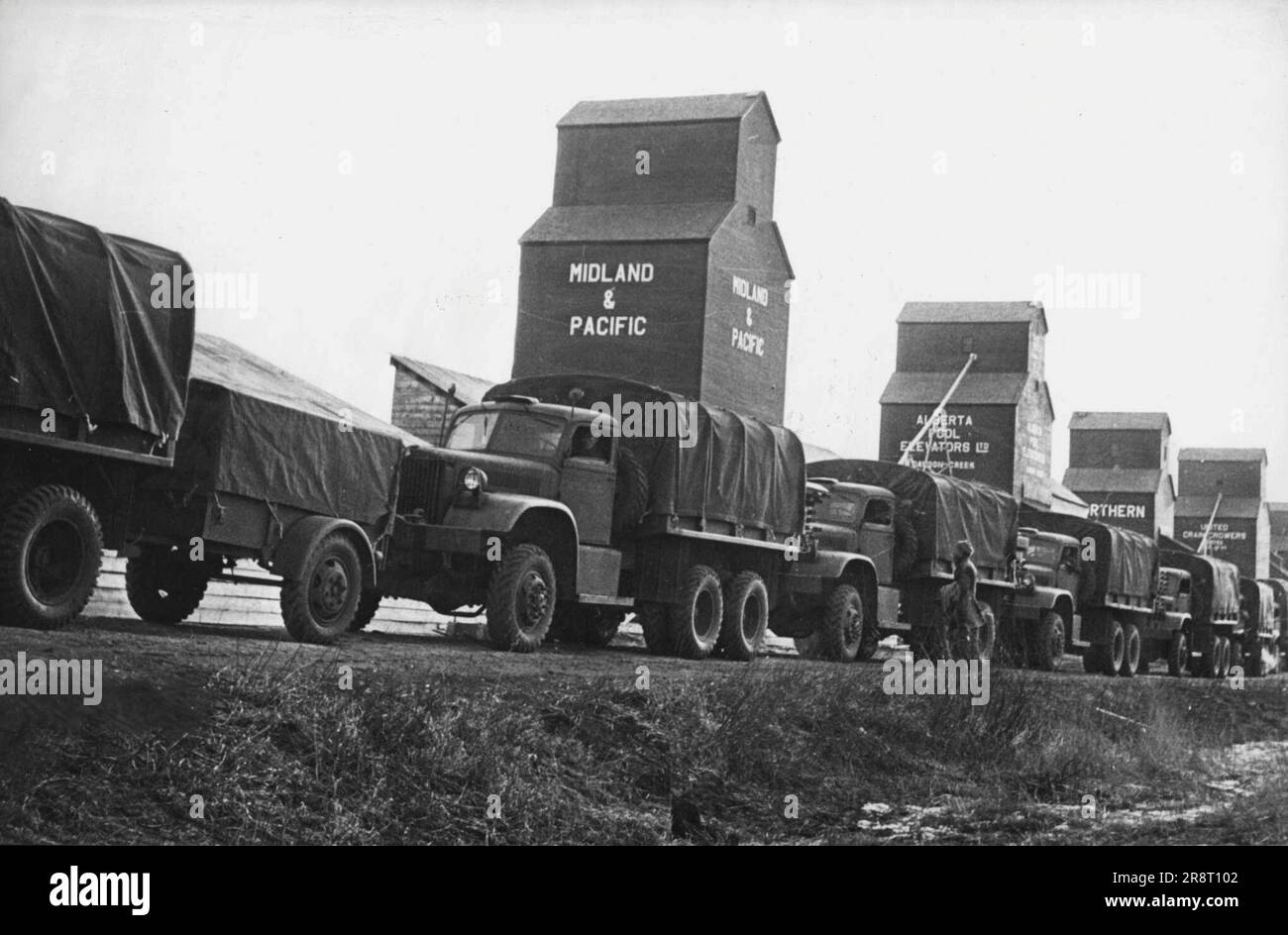 STATI UNITI Autostrada per Alaska -- Un convoglio degli Stati Uniti I camion dell'esercito passano gli elevatori canadesi del grano in qualche luogo lungo l'autostrada di Alcan fra gli Stati Uniti e l'Alaska. La strada è ora aperta e le munizioni e le forniture vengono trasportate ai posti militari nell'estremo nord. Marzo 28, 1943. (Foto di Interphoto News Pictures, Inc.) Foto Stock