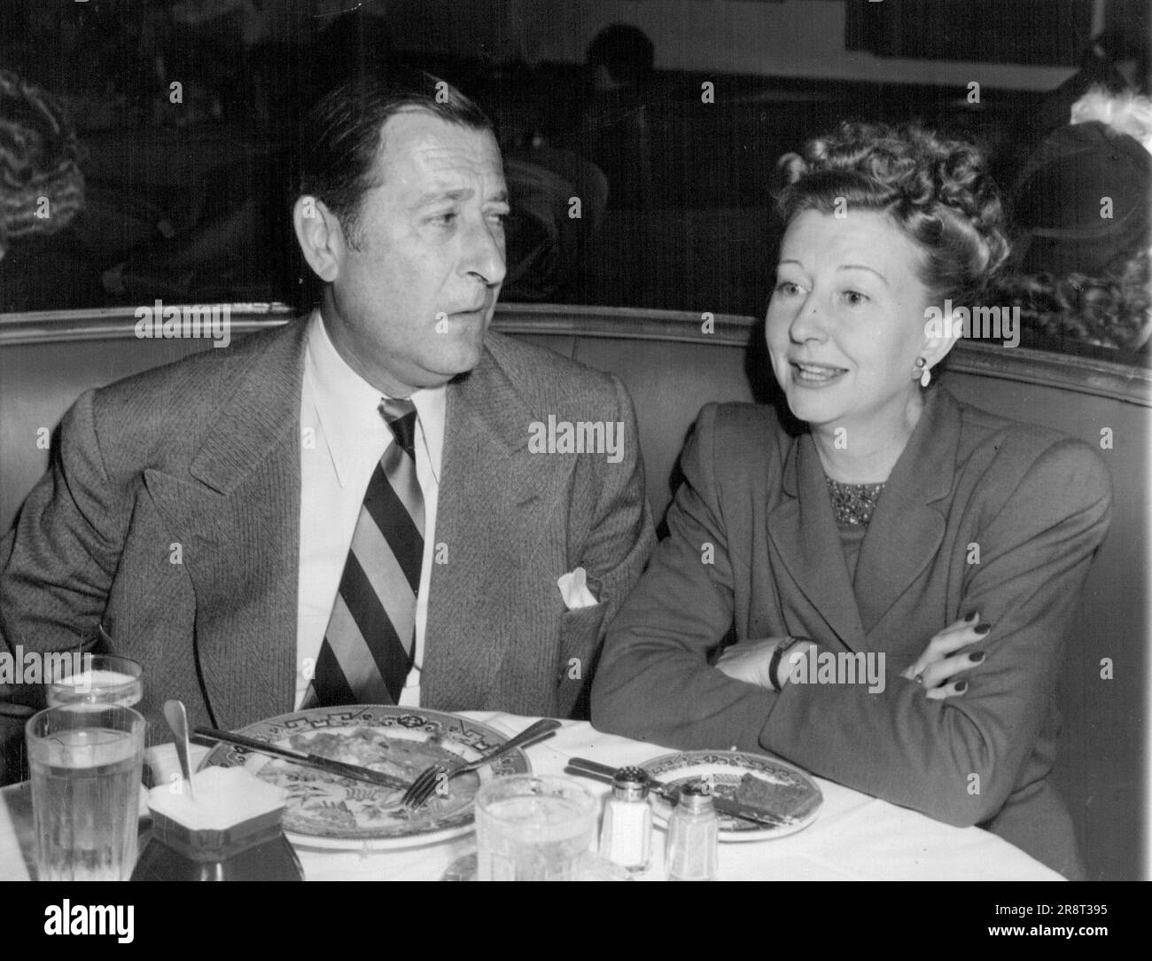 Chow Time for Screen Personalities: L'attore Arthur Treacher, noto per la sua abilità di maggiordomo, è mostrato qui sull'altro lato del servizio al Brown Derby Restaurant. Sta pranzando con Irene Ryan, un'attrice radio. Arthur Treacher, alto e impeccabile inglese, conosciuto da generazioni di registi come il maggiordomo perfetto, ha in programma di entrare nel business del maggiordomo. Treacher, 71 anni, e ora una personalità televisiva, ha annunciato la formazione di un'organizzazione di franchising che userà il suo nome e la sua immagine per vendere servizi temporanei di maggiordomo, cameriera e tuttofare. 16 febbraio 1947. (PH… Foto Stock