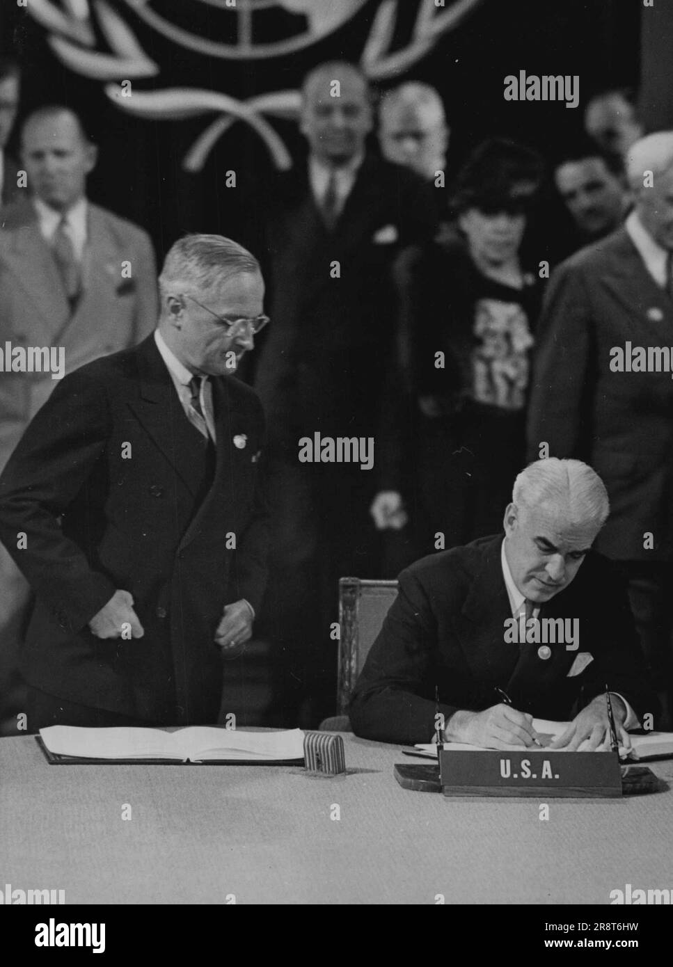Truman Watches Stettinius segno per gli Stati Uniti -- come guarda il Presidente Truman, il Segretario di Stato Stettinius (seduto) firma il capitolo delle Nazioni Unite a San Francisco, giugno 26. Le persone in background non sono identificate. Giugno 26, 1945. (Foto per foto stampa associata). Foto Stock
