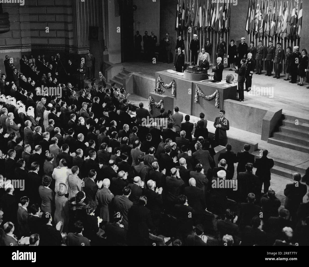 I delegati plaudono a Truman -- i delegati delle Nazioni Unite si alzano in piedi e applaudono quando il presidente Truman entra nel rostro per affrontare la sessione conclusiva della conferenza delle nove settimane a San Francisco, il 26 giugno. A destra di Truman c'è il segretario di Stato Stettinius. Giugno 26, 1945. (Foto per foto stampa associata). Foto Stock