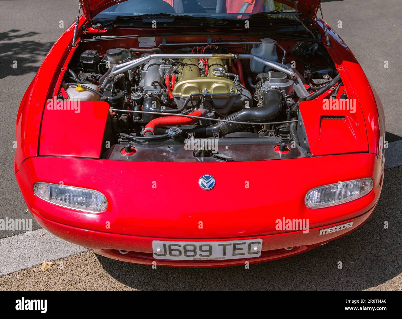 Una vista dettagliata sotto il cofano di un'elegante Mazda MX-5, che mostra il motore che alimenta questa iconica roadster giapponese. Foto Stock