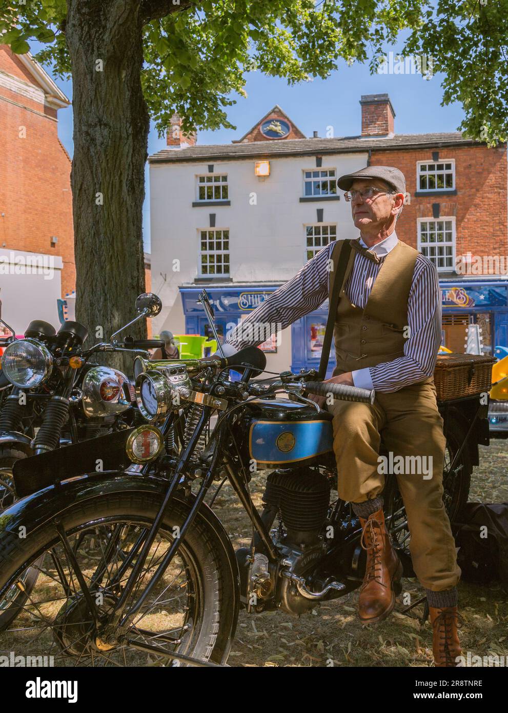 Un ritratto dell'orgoglioso proprietario di una motocicletta Triumph Model NSD in piedi accanto alla sua motocicletta mentre indossa un costume d'epoca. Moto d'epoca. Foto Stock