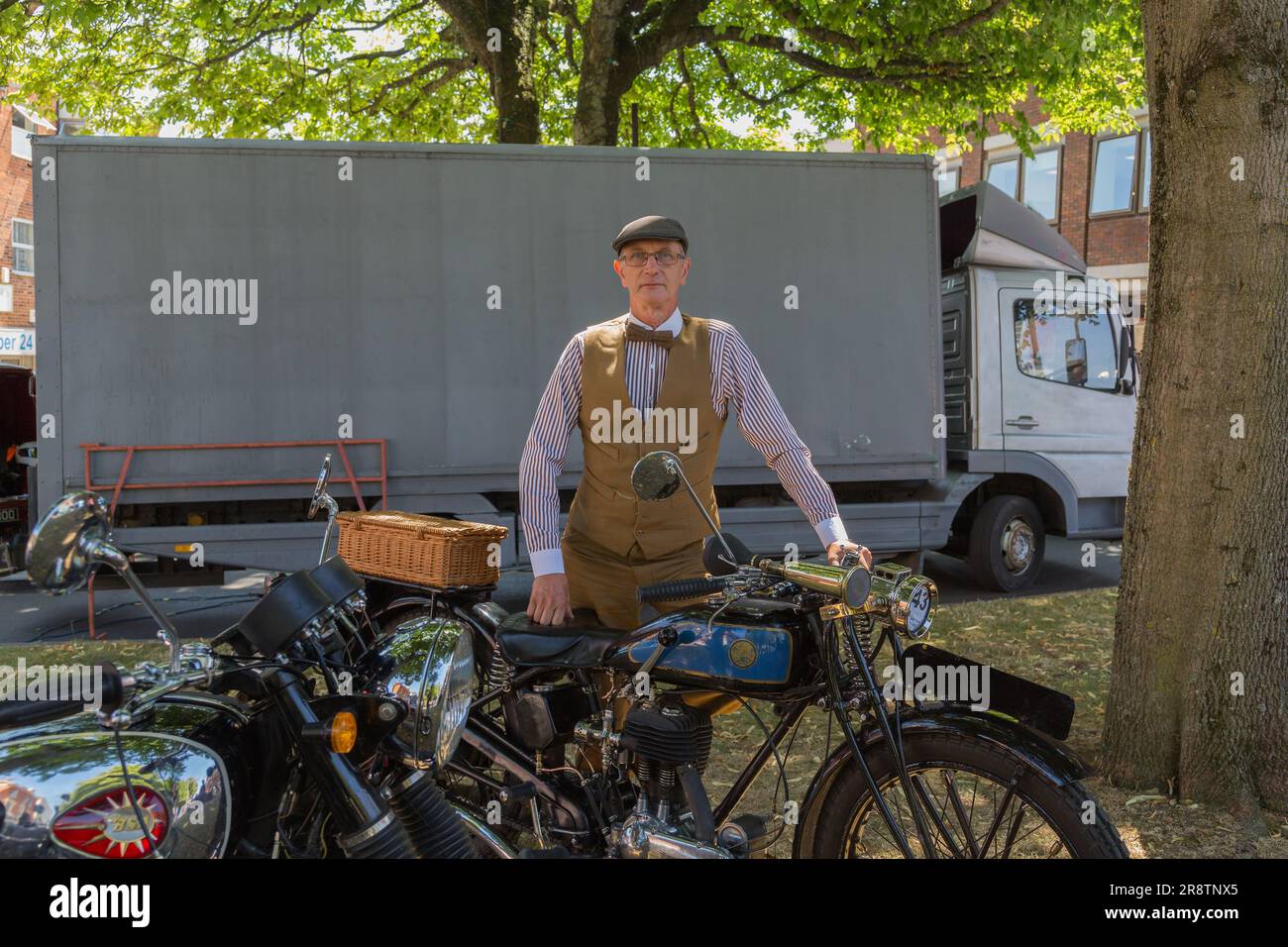 Un ritratto dell'orgoglioso proprietario di una motocicletta Triumph Model NSD in piedi accanto alla sua motocicletta mentre indossa un costume d'epoca. Moto d'epoca. Foto Stock
