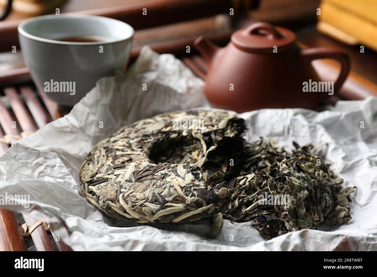 Tè pu-erh rotto a forma di disco su vassoio di legno, primo piano. Cerimonia tradizionale Foto Stock