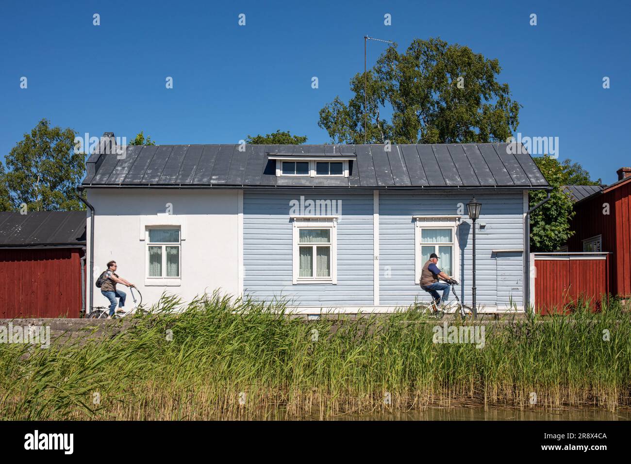 Persone in bicicletta che passano davanti a una vecchia casa sul lungomare di Eteläinen Rantakatu 4 nel quartiere Barckens udde di Tammisaari, Finlandia Foto Stock