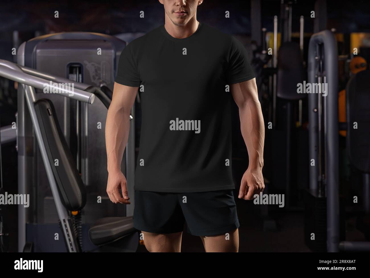 Modello di t-shirt nera su un atleta sullo sfondo dell'inventario in palestra, abbigliamento sportivo di qualità per design, stampa, vista frontale. Camicia elegante mo Foto Stock