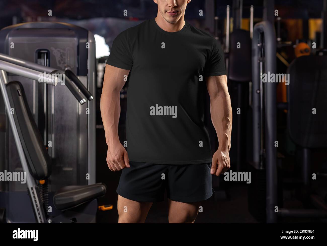 Modello di t-shirt nera su uno sfondo palestra, dalla testa alle ginocchia, abbigliamento sportivo in texture per il design e la vista frontale. Mockup di una camicia di qualità Foto Stock