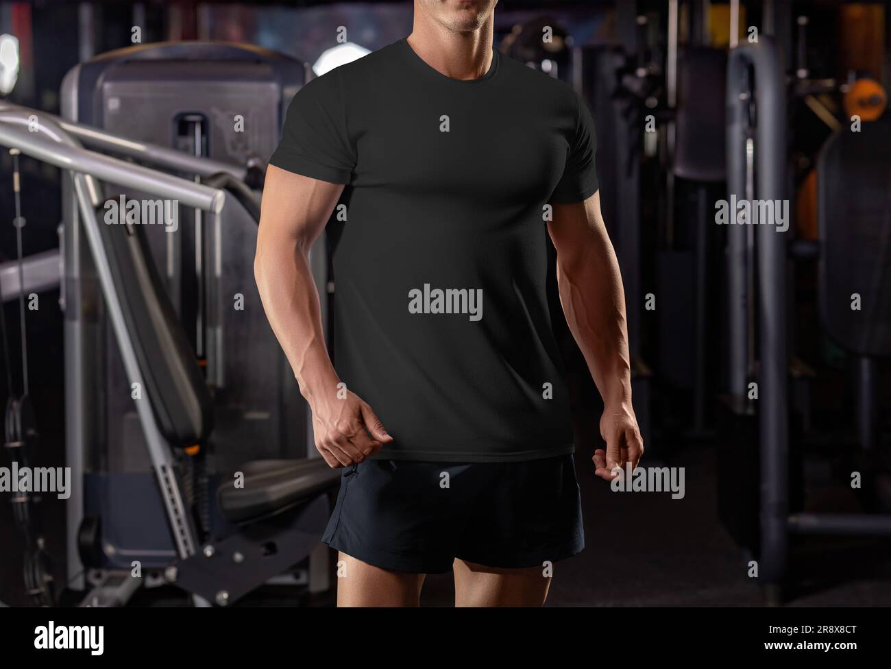 Modello di t-shirt nera su un atleta in posa sullo sfondo della palestra, dalla testa alle ginocchia, dall'abbigliamento sportivo alla vista frontale. Mockup di una camicia su un uomo beefy, Foto Stock