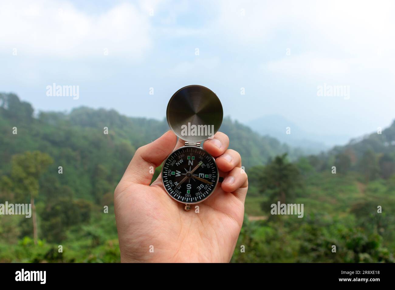 Ideale per viaggi e avventure. Una bussola tenuta a mano con vista montagnosa, dopo alcune modifiche. Foto Stock