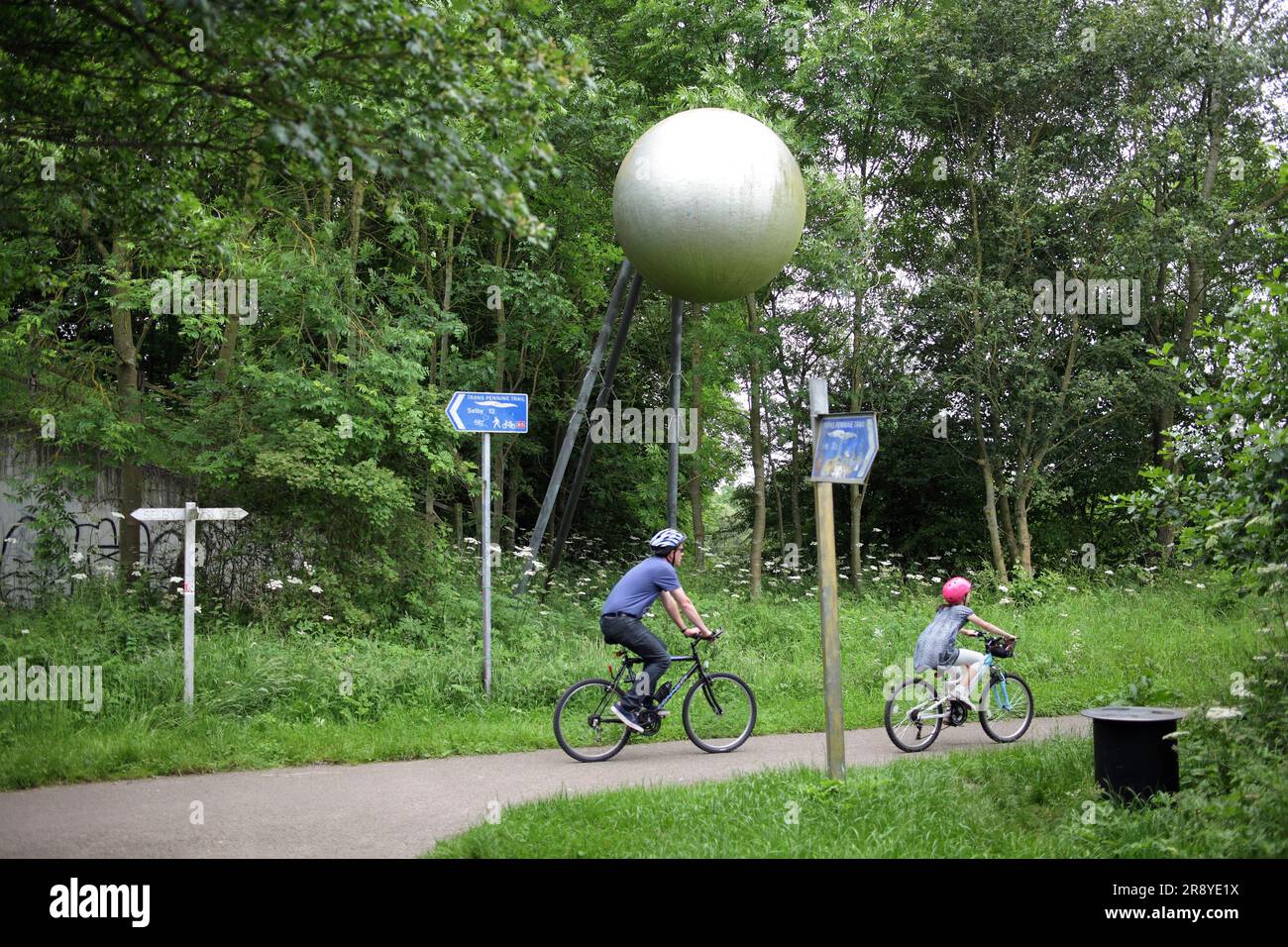 I ciclisti passano un modello del sole all'inizio della pista ciclabile "Cycle the Solar System" di York, utilizzando il percorso di una linea ferroviaria in disuso. Foto Stock