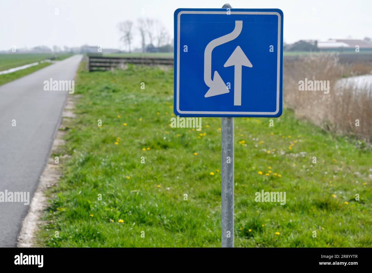 Strada stretta in una zona rurale e segnaletica con le istruzioni per il passaggio del traffico. Foto Stock