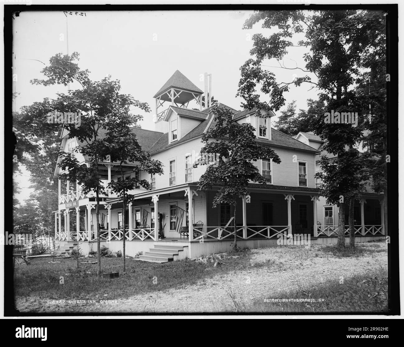 Omena Inn, Omena, tra il 1890 e il 1901. Hotel del Michigan con veranda in legno, bandiere statunitensi e sedie a dondolo. Foto Stock