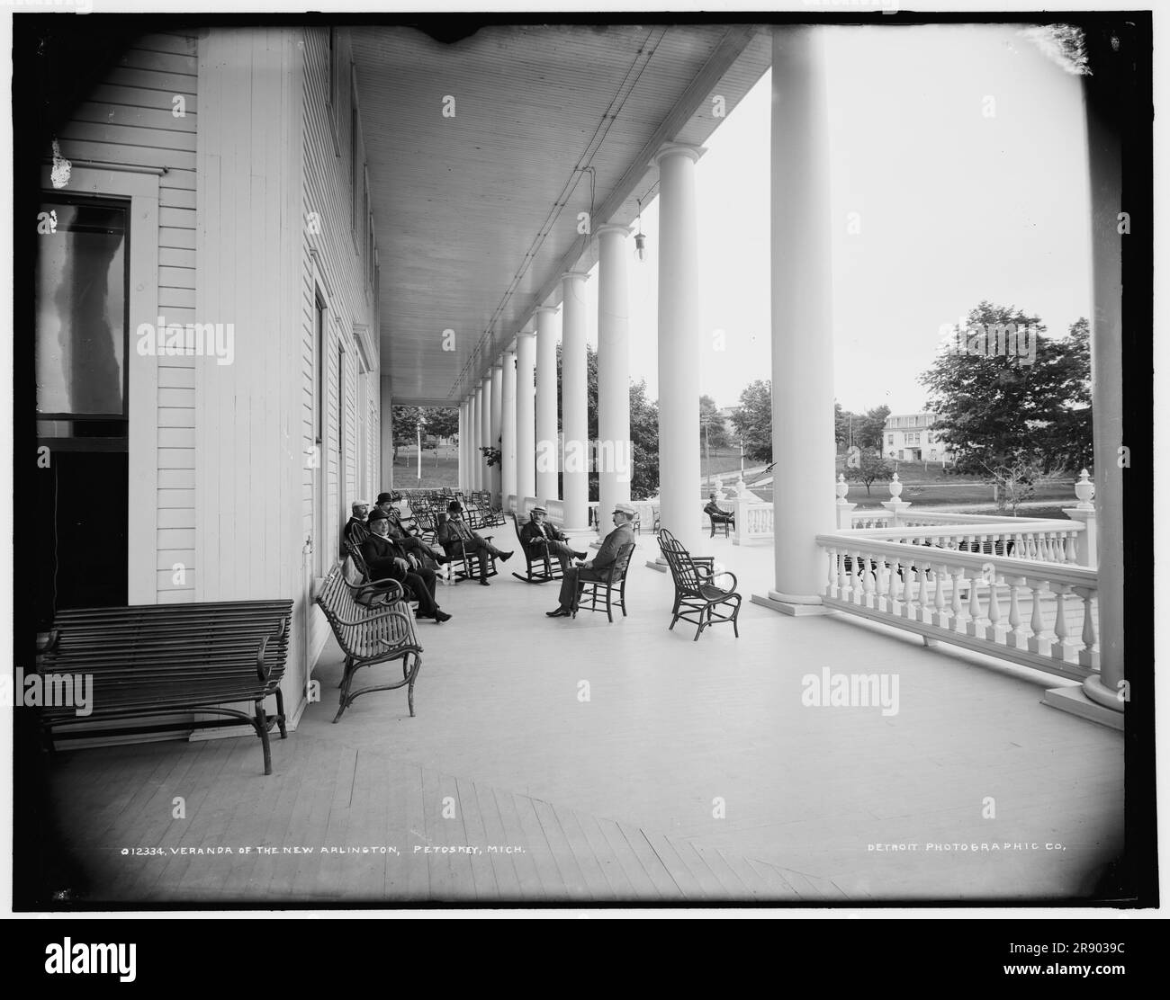 Veranda del New Arlington Hotel, Petoskey, Mich., tra il 1890 e il 1901. Gli uomini che indossano cappelli da bowling e diportisti in paglia si rilassano sulle sedie a dondolo. Foto Stock